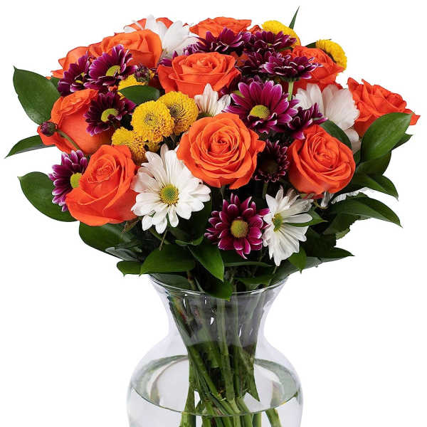 Mixed bouquet of orange roses and assorted daisies in a clear glass vase