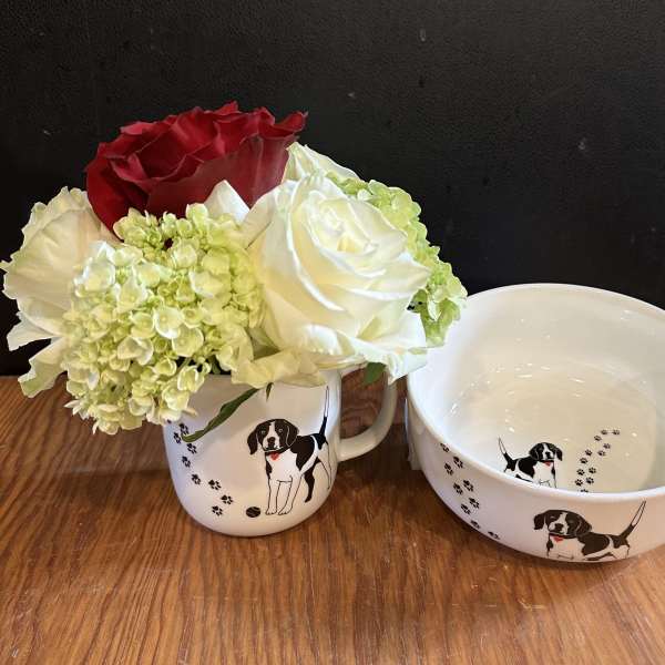 Small bouquet of red, white, and pale green flowers in a dog-print mug beside a matching bowl
