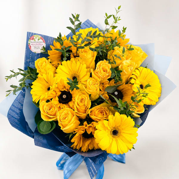Yellow roses and gerbera daisies in blue wrapping with ribbon