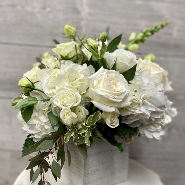 White roses and hydrangeas arranged in a square box with greenery