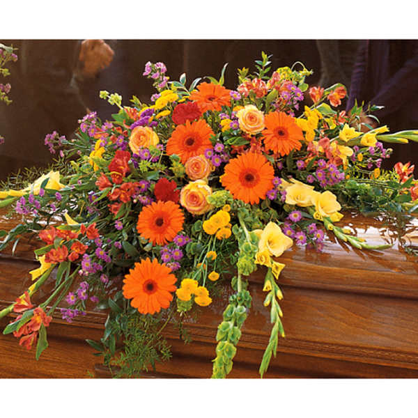 Colorful floral casket spray with orange gerberas, yellow callas, and purple accents