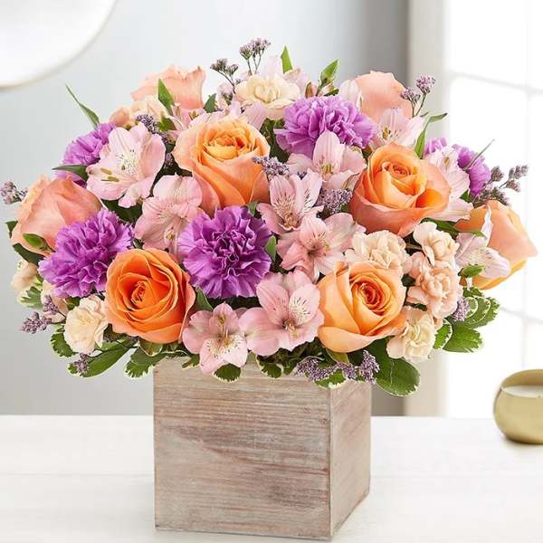 Peach and purple flower arrangement in a wooden box