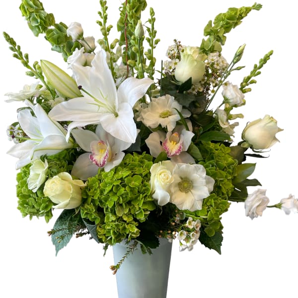 White lilies and orchids in a tall gray vase with green hydrangeas