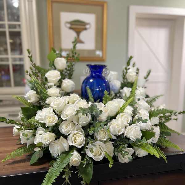 White rose arrangement with ferns and eucalyptus on a table
