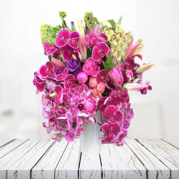 Pink orchid arrangement in a white vase