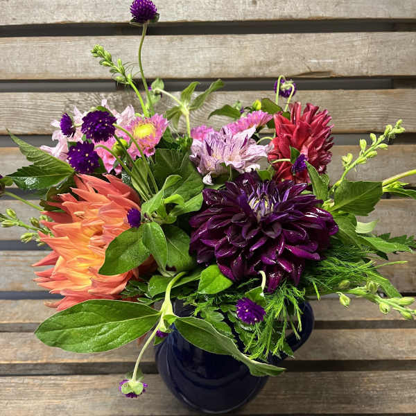 Colorful mixed bouquet in a dark vase with purple, pink, and coral blooms