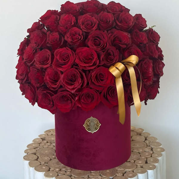 Large bouquet of red roses in a burgundy hatbox with a gold ribbon