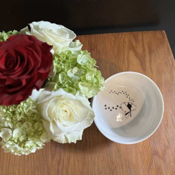 Bouquet of red and white roses with green hydrangeas beside a small white bowl