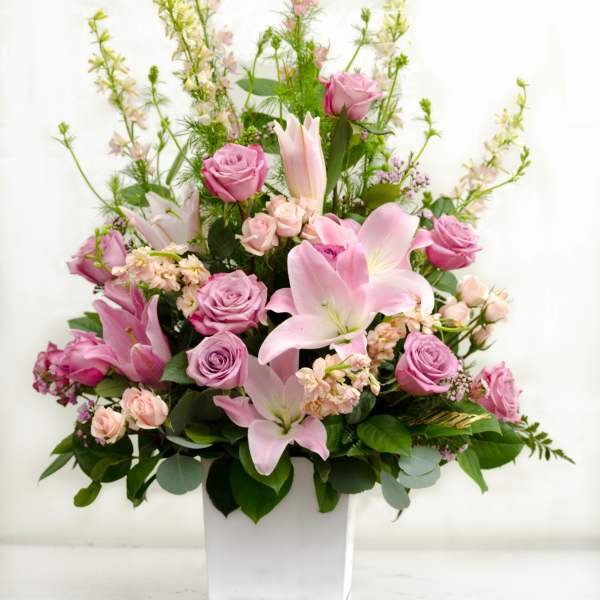 Pink roses and lilies arranged in a white vase