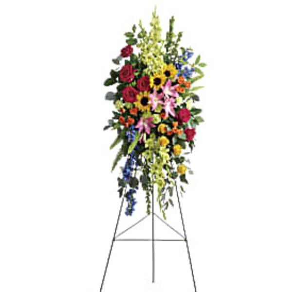 Tall standing spray with red roses, pink lilies, sunflowers and mixed blooms on a metal easel.