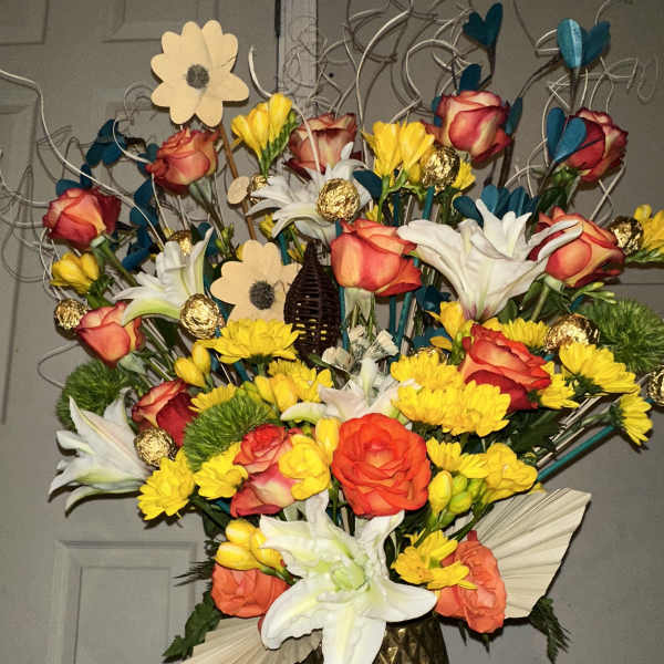 Colorful bouquet of roses, lilies, and yellow daisies in a gold vase