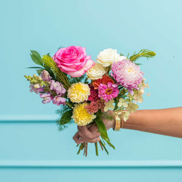 Handheld bouquet of pink and white flowers with mixed blooms
