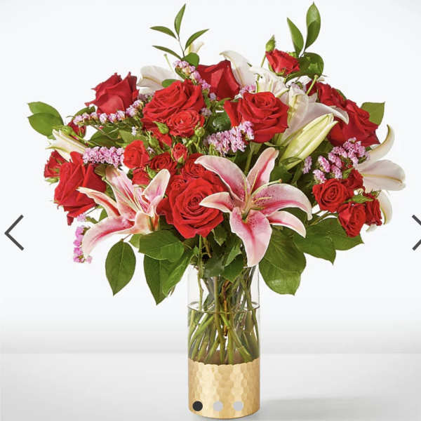 Bouquet of red roses and pink lilies in a clear glass vase