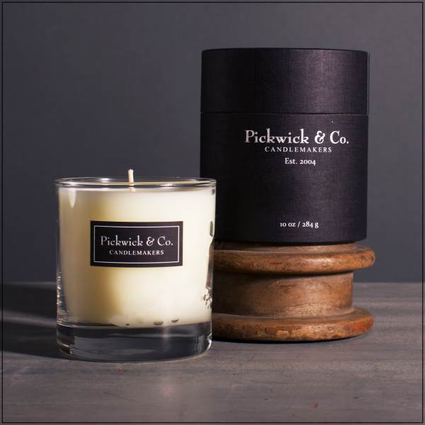 Glass candle with black labeled box on a wooden spool