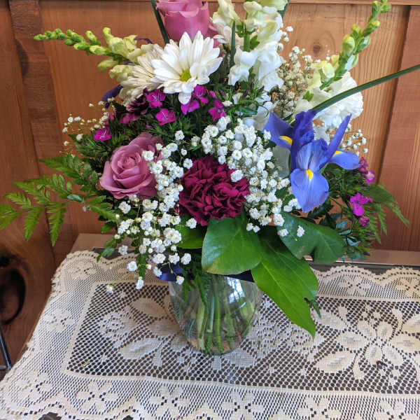 Mixed bouquet in a glass vase with roses, daisies, iris, and snapdragons