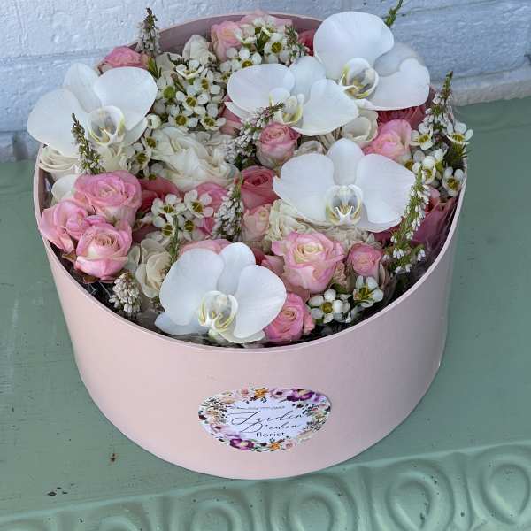 Pink and white bouquet in a round box with orchids and roses
