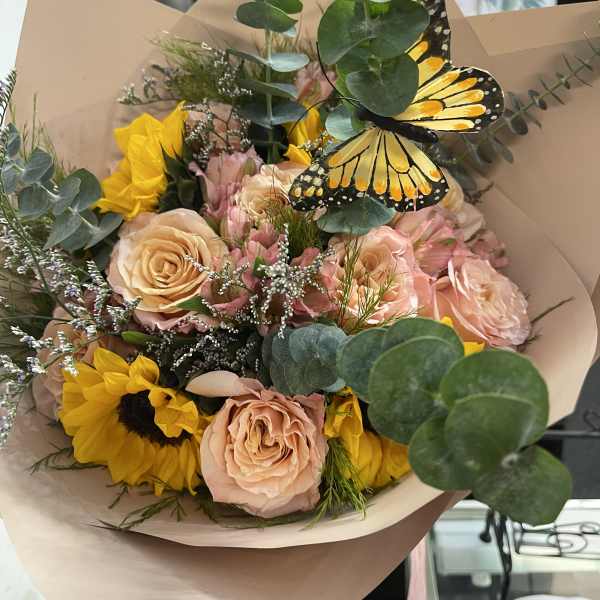Bouquet of peach roses and sunflowers with a butterfly accent