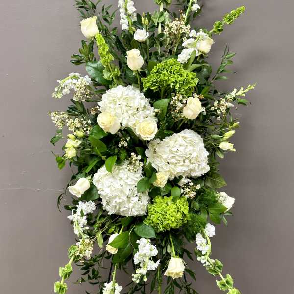 Tall standing spray of white roses and hydrangeas with green accents on an easel stand