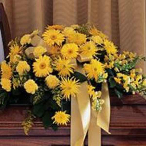 Yellow floral casket spray with a cream ribbon