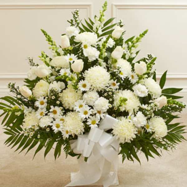 White floral standing spray with daisies, carnations, and a white ribbon