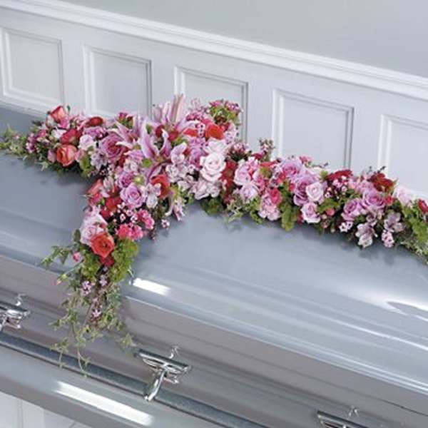Pink and lavender floral spray on a silver casket