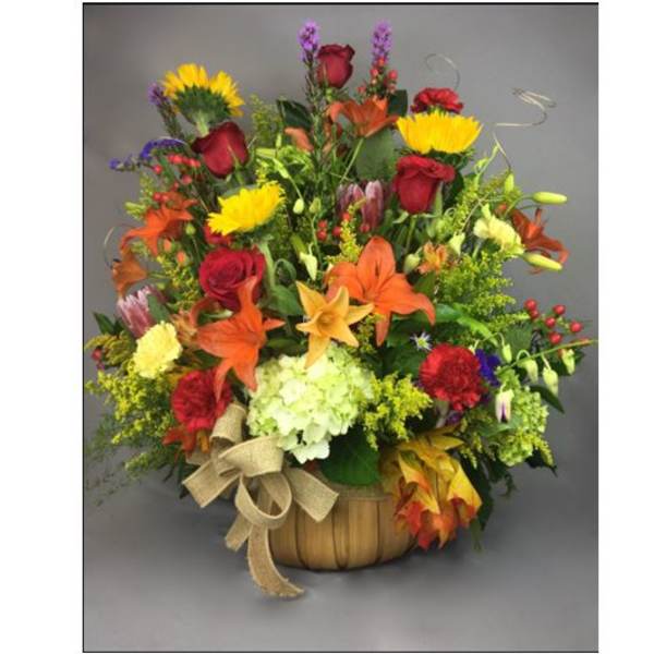 Mixed bouquet in a basket with red roses, lilies, and yellow blooms