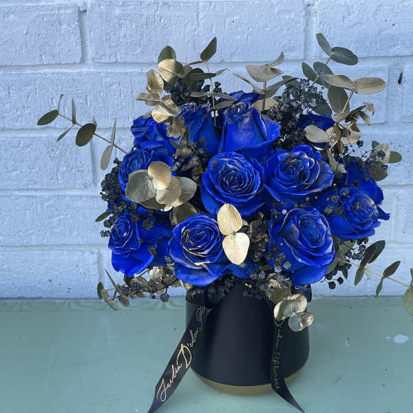 Blue roses in a black vase with gold foliage accents