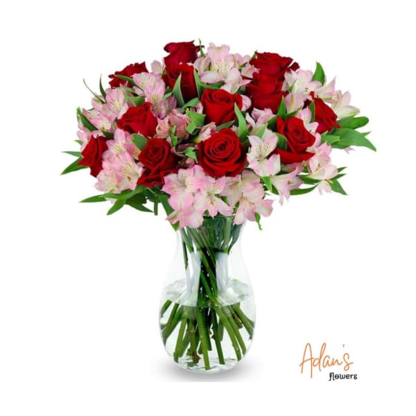 Red roses and pink alstroemeria in a clear glass vase