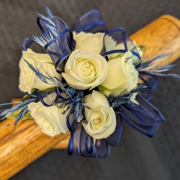 Small cluster of ivory roses with navy ribbon and blue accents on a wooden handle