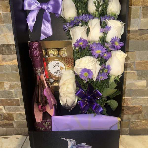 Gift box with white roses, purple flowers, champagne, and chocolates