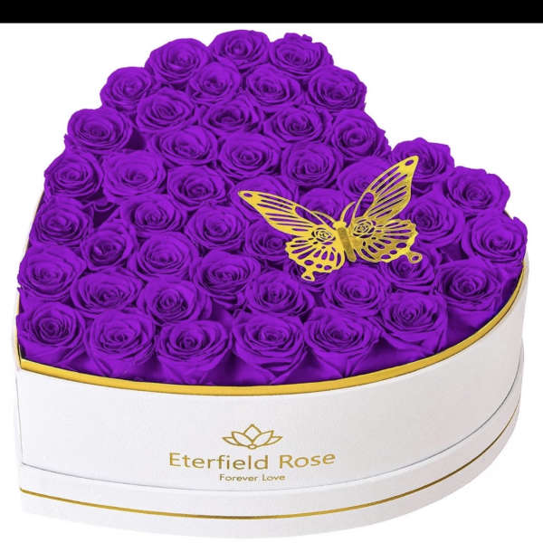 Heart-shaped box filled with purple roses and a gold butterfly topper