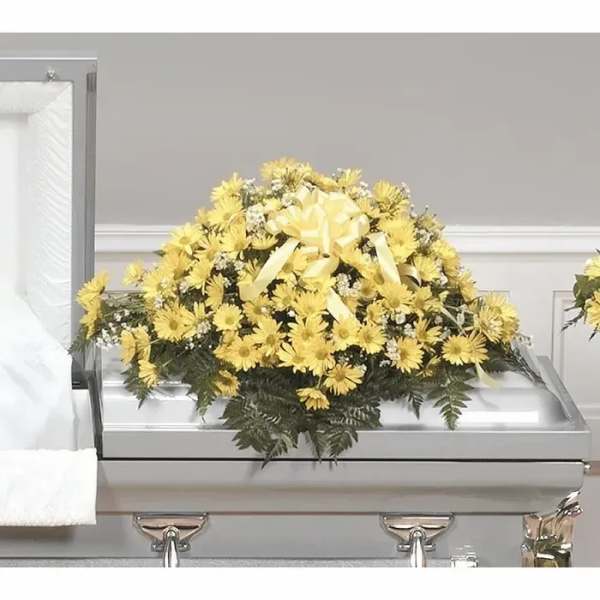 Yellow floral casket spray with a ribbon on a silver casket