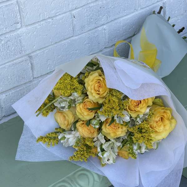 Bouquet of yellow roses and white flowers wrapped in white paper