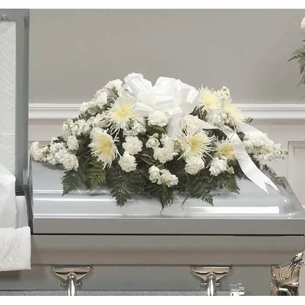 White floral casket spray with a large ribbon on a silver casket