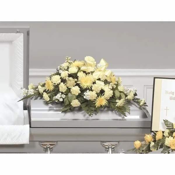 Cream and yellow floral spray on a silver casket
