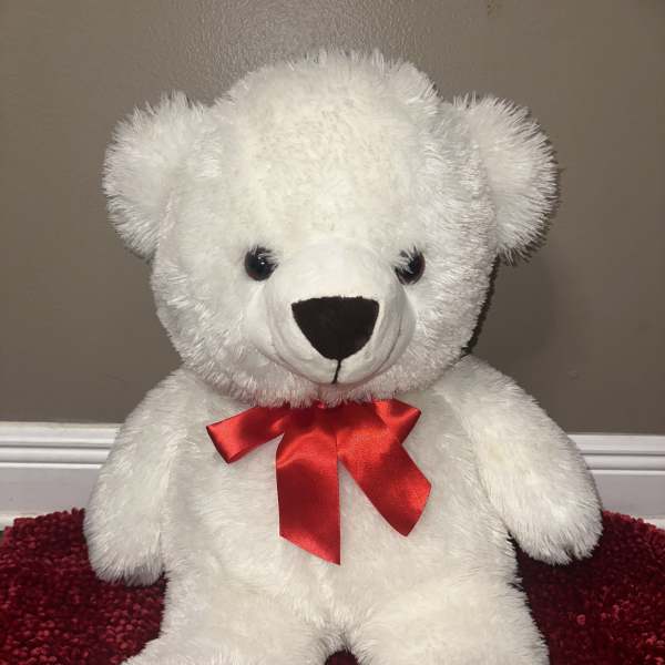 White teddy bear with a red ribbon bow