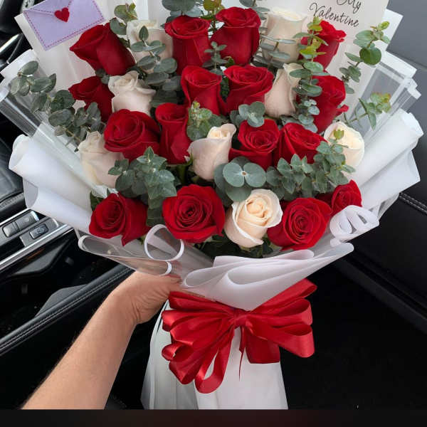 Bouquet of red and white roses with eucalyptus, wrapped in white paper and a red ribbon