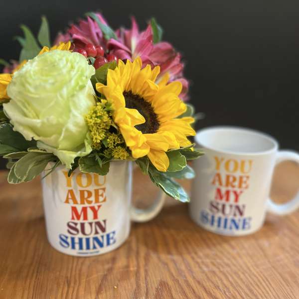 Flower arrangement in a mug with a sunflower and pink blooms