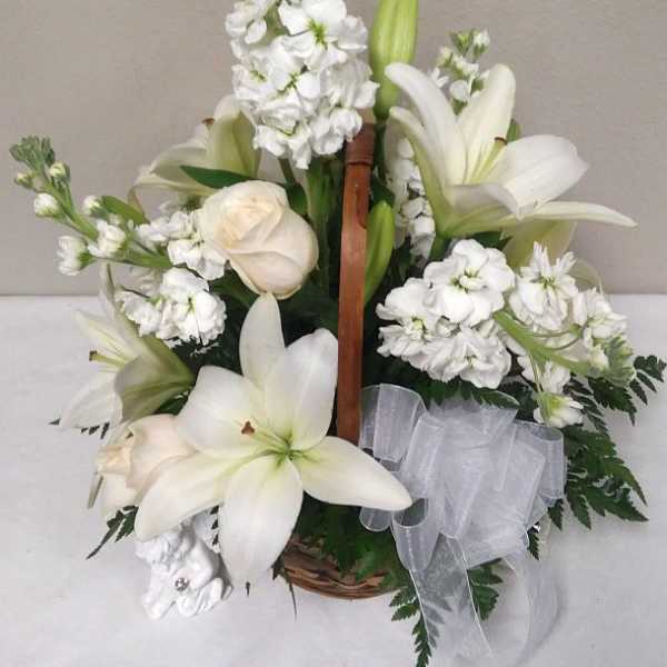 White lilies and white flowers arranged in a basket with a sheer ribbon