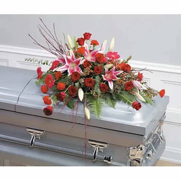 Red and pink floral casket spray on a silver casket