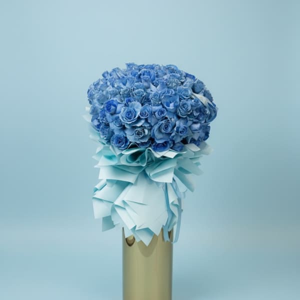 Blue rose bouquet with a pale ribbon wrap in a gold vase