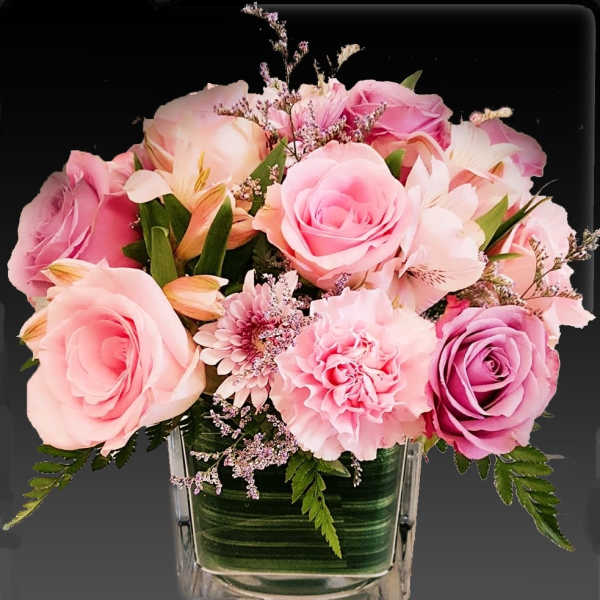 Pink roses and carnations in a clear square vase