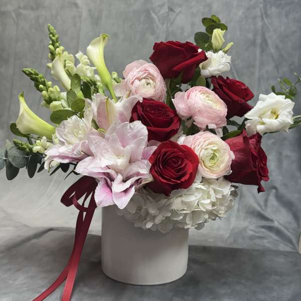 Bouquet of red and pink roses with white blooms in a white vase