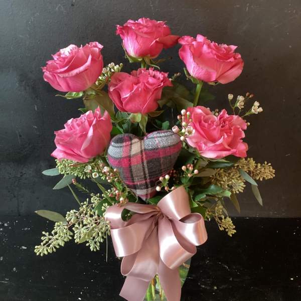 Pink roses in a glass vase with a plaid heart and satin bow