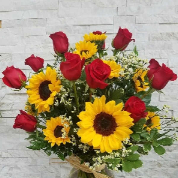 Bouquet of red roses and yellow sunflowers in a glass vase