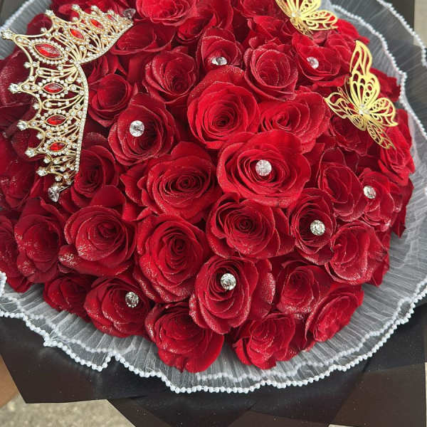 Bouquet of red roses with gold butterfly accents and a jeweled crown decoration