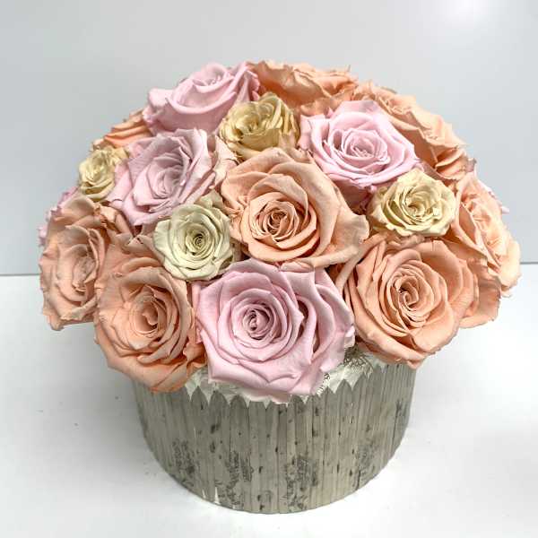Round bouquet of pastel roses in a textured silver container