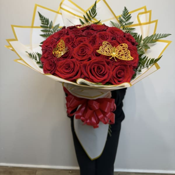 Bouquet of red roses with gold butterfly accents and white-gold wrapping