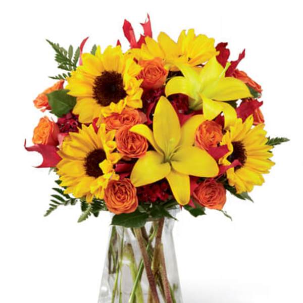 Sunflowers and orange roses in a clear glass vase