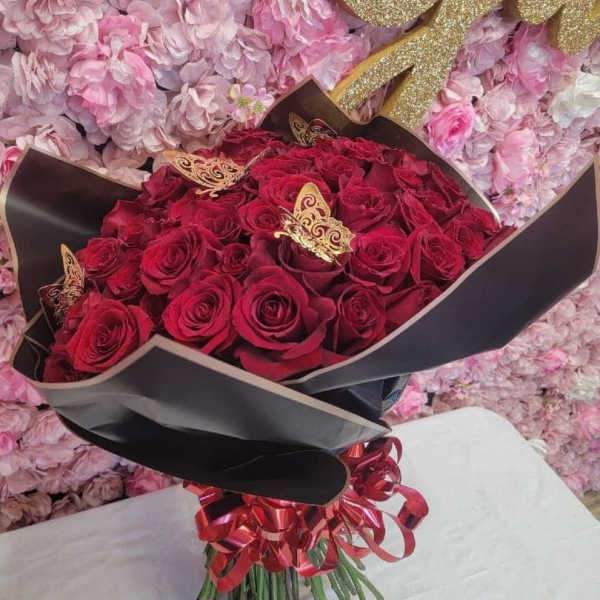 Bouquet of red roses wrapped in black paper with a red ribbon